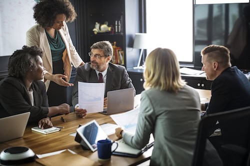 A team sits around a table discussing the steps to take when scaling a business considering the benefits of freelance talent.