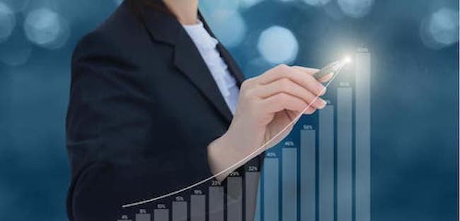 A small business owner standing behind a graph showing an upward trend suggesting that flexibility and a quality talent strategy were a part of her growth strategy