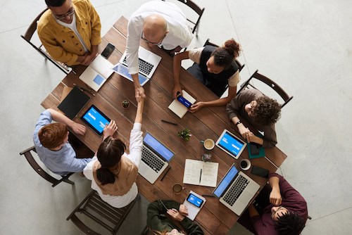 A team of workers sits around a table as the manger leads them to success. 