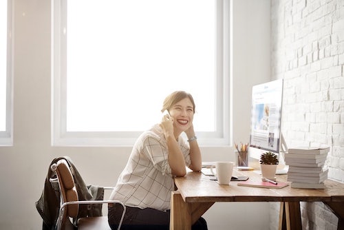 A freelancer or contract worker talking on the phone while running their small business. 