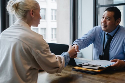 A small business owner looking to hire a freelancer is shaking hands with a potential employee.