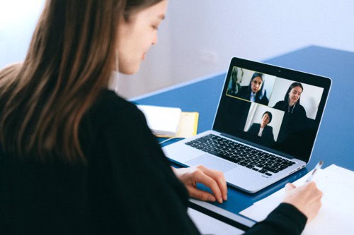 A business owner who is employing a freelancer is sitting in front of a computer for a virtual interview. 