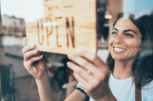 A small business owner puts up an open sign during a recession.