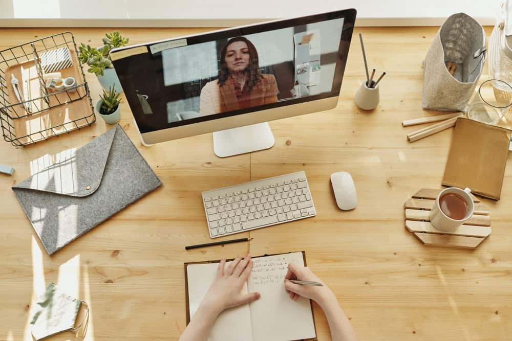 Woman on a video chat taking notes.