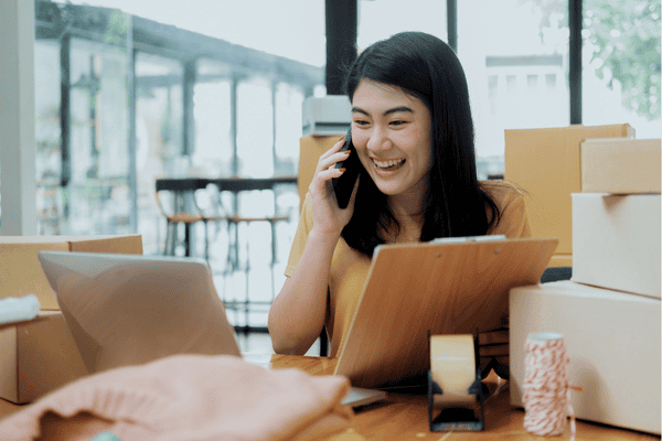 A freelance online business manager making a phone call while supporting an online seller business.